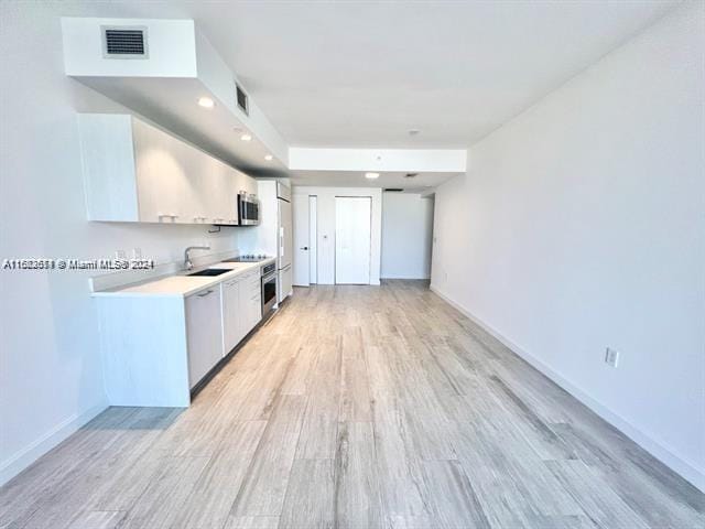 kitchen with light hardwood / wood-style flooring, stainless steel appliances, white cabinetry, and sink