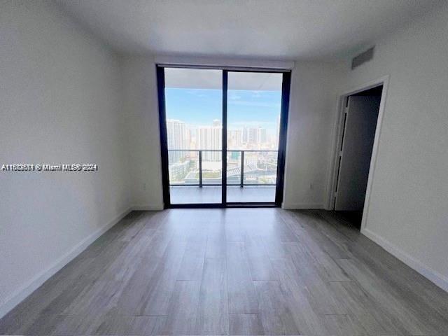 45 SW 9th St Unit 3009, Miami, FL 33130 - unfurnished room with expansive windows, wood finished floors, and baseboards