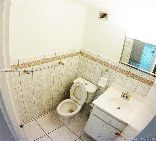 bathroom featuring vanity, tile walls, tile patterned flooring, and toilet