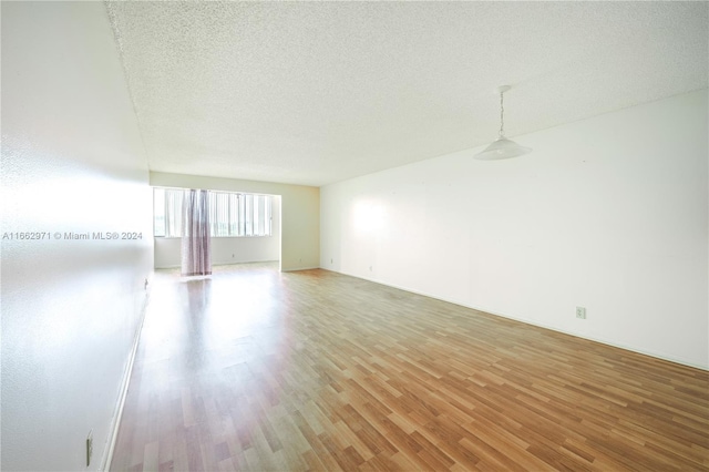 spare room featuring wood-type flooring and a textured ceiling