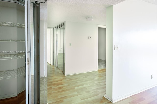 corridor featuring light hardwood / wood-style flooring and a textured ceiling