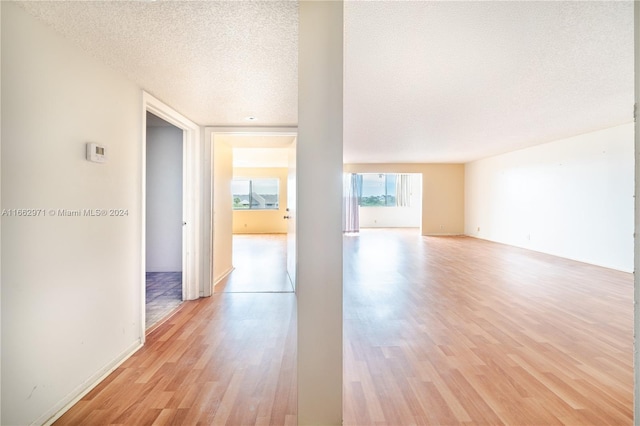 empty room with a textured ceiling and light hardwood / wood-style flooring