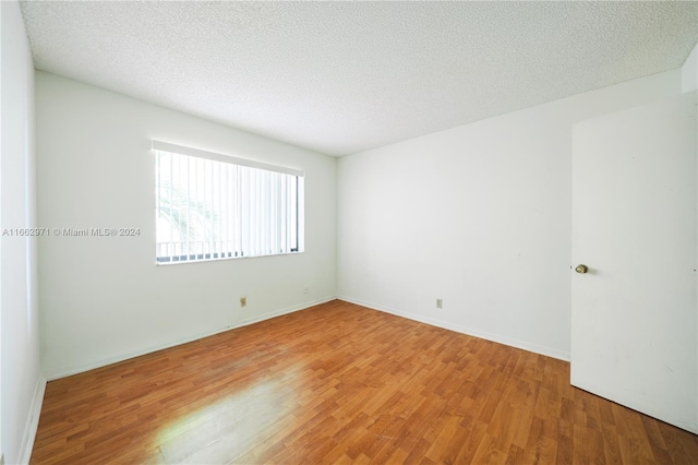 spare room featuring a textured ceiling and hardwood / wood-style floors