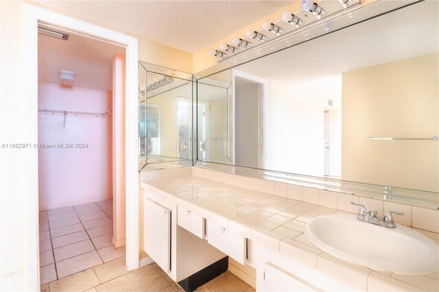 bathroom with a textured ceiling, vanity, and tile patterned floors