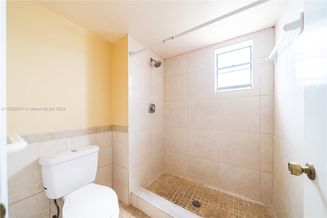 bathroom with tile walls, toilet, and tiled shower