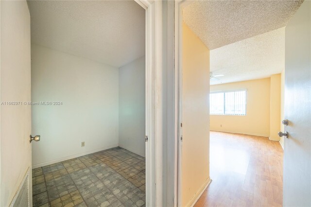 hall featuring a textured ceiling and light wood-type flooring