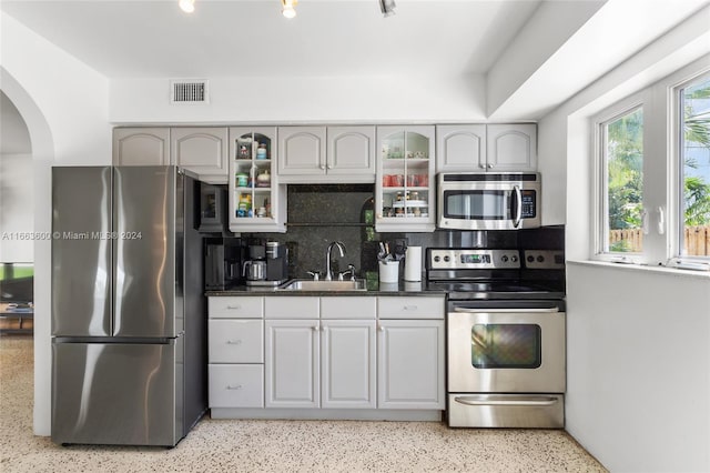 kitchen with appliances with stainless steel finishes, sink, gray cabinets, and tasteful backsplash