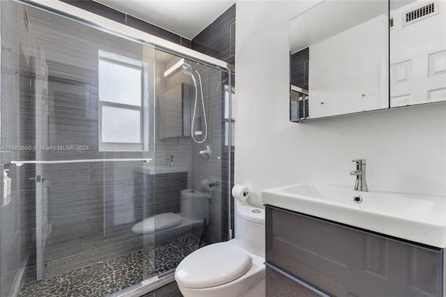 bathroom featuring walk in shower, vanity, and toilet