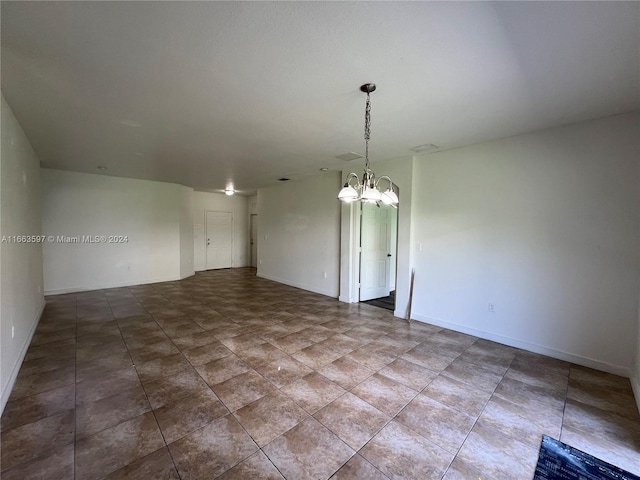 unfurnished room featuring a notable chandelier