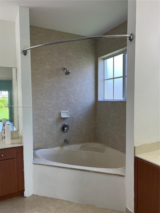 bathroom featuring tile patterned flooring, vanity, tiled shower / bath, and vaulted ceiling