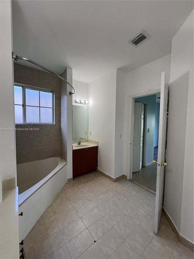 bathroom featuring tile patterned flooring, vanity, and tiled shower / bath