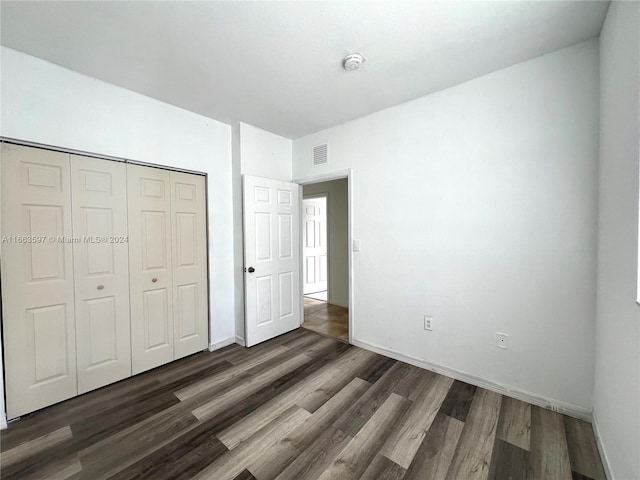 unfurnished bedroom with a closet and dark wood-type flooring