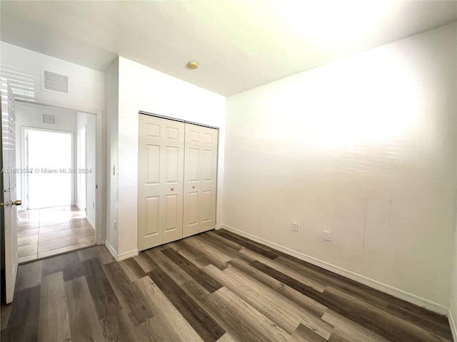 unfurnished bedroom with a closet and dark hardwood / wood-style flooring