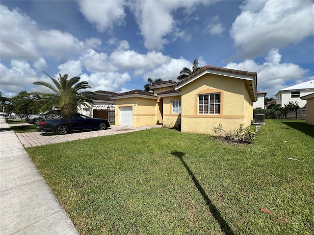 view of front facade featuring a front yard, central AC, and a garage