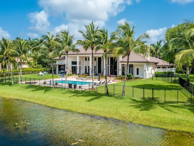 rear view of property featuring a patio, a fenced in pool, a water view, and a yard