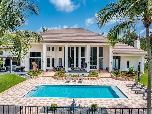 rear view of house with a fenced in pool and a patio area