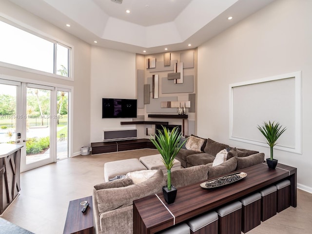 living room with french doors, a raised ceiling, and a towering ceiling