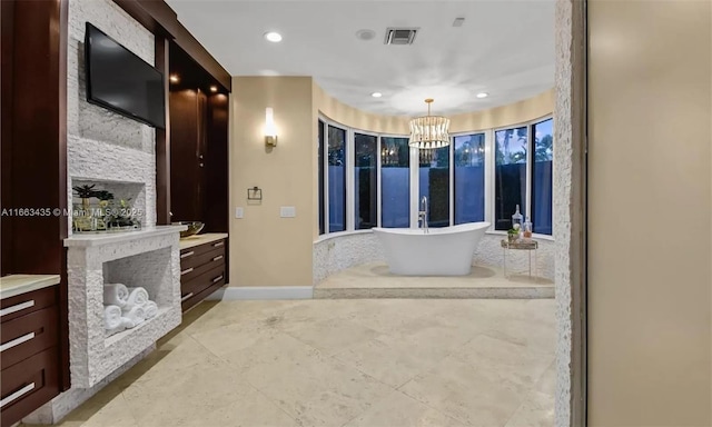 bathroom with vanity, a bath, a notable chandelier, and a fireplace