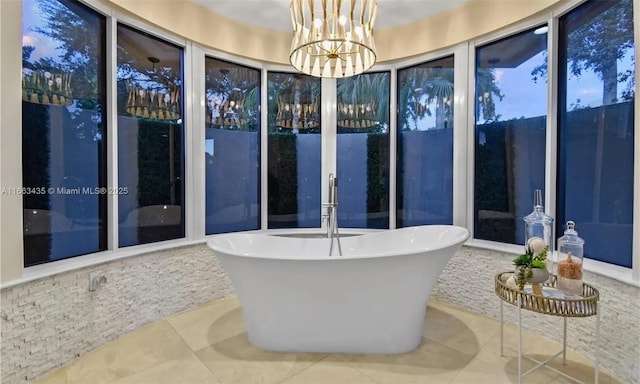 bathroom with a washtub, tile patterned floors, and a notable chandelier