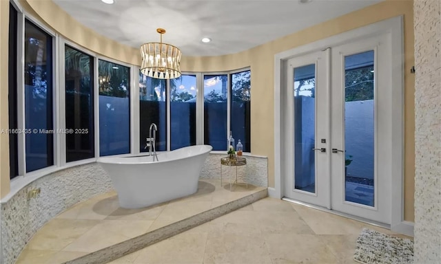 bathroom featuring a notable chandelier, a washtub, and french doors