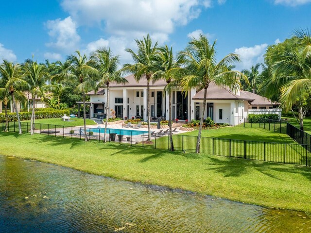 rear view of house featuring a lawn, a fenced in pool, a patio area, and a water view