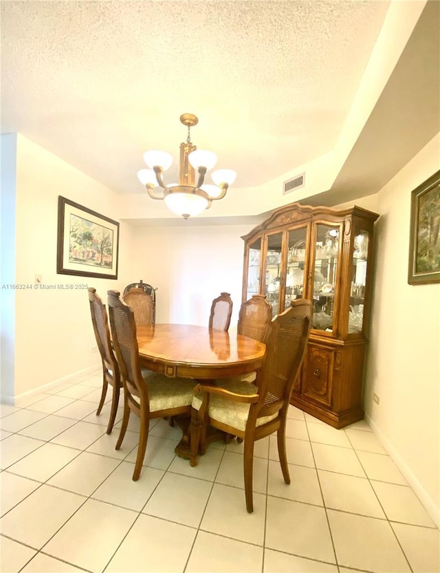 tiled dining space featuring a textured ceiling and an inviting chandelier