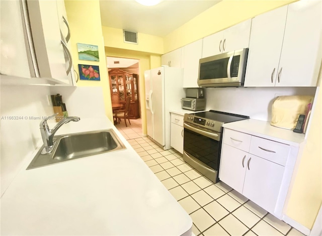 kitchen with light tile patterned flooring, stainless steel appliances, sink, and white cabinets