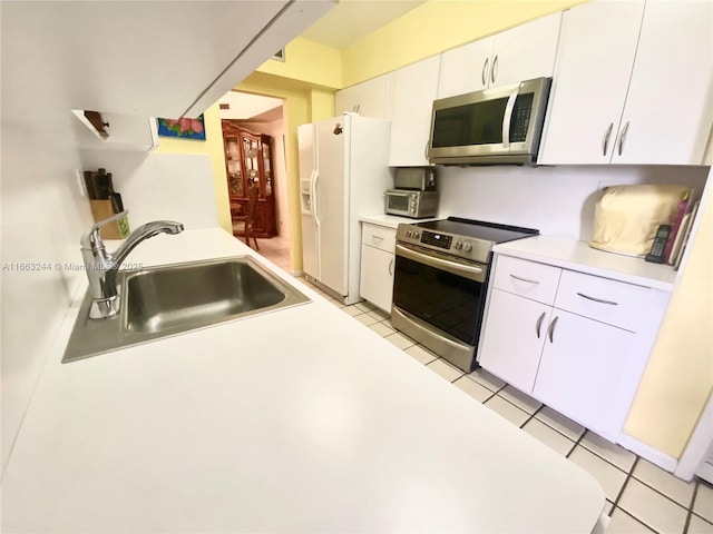 kitchen featuring stainless steel appliances, light tile patterned flooring, sink, and white cabinets