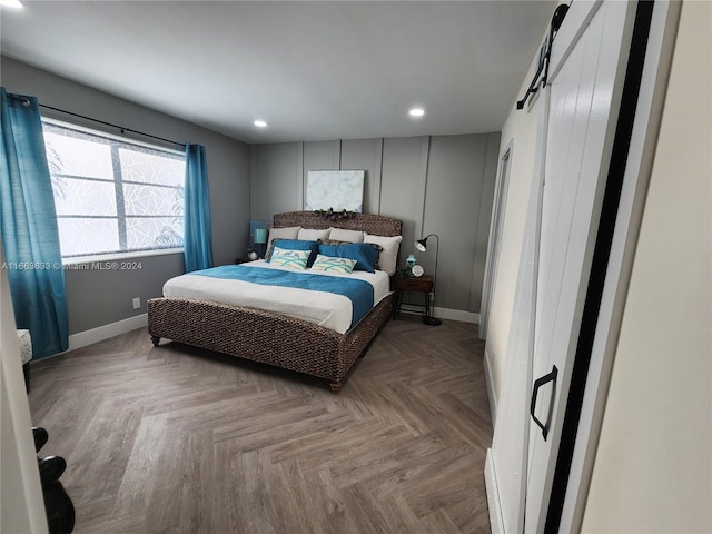 bedroom with a barn door and parquet floors