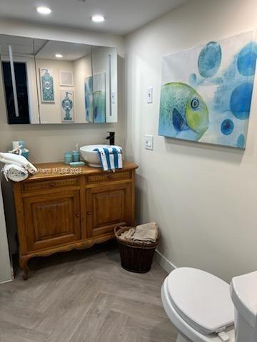 bathroom featuring parquet flooring, vanity, and toilet