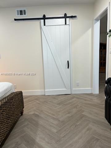 bedroom with a barn door and parquet flooring