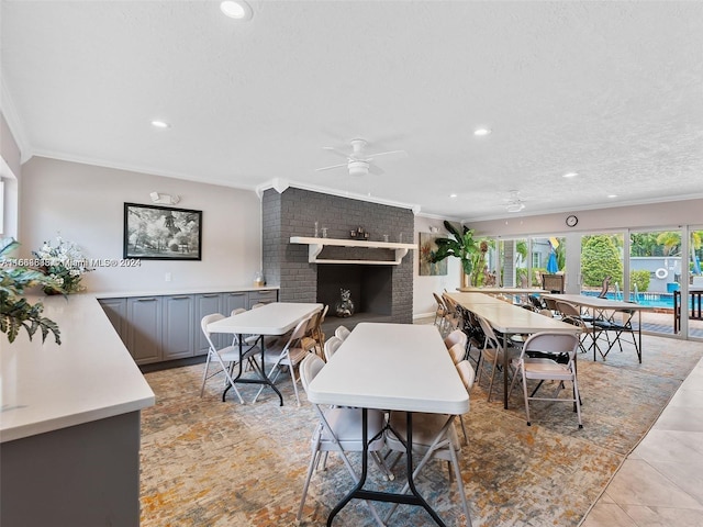 tiled dining room with crown molding, a fireplace, ceiling fan, and a textured ceiling