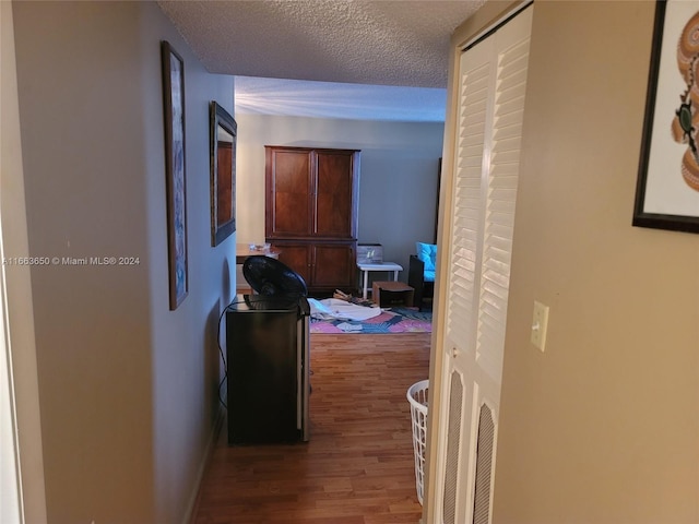 corridor with a textured ceiling and hardwood / wood-style flooring