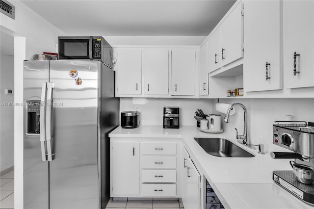 kitchen with light tile patterned flooring, stainless steel fridge with ice dispenser, white cabinetry, and sink