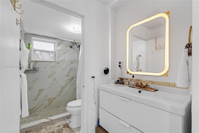 bathroom with a tile shower, vanity, and toilet