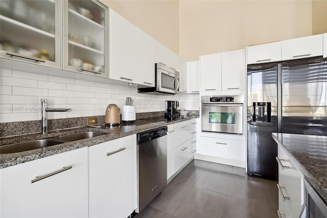 kitchen with decorative backsplash, white cabinetry, dark stone counters, sink, and stainless steel appliances