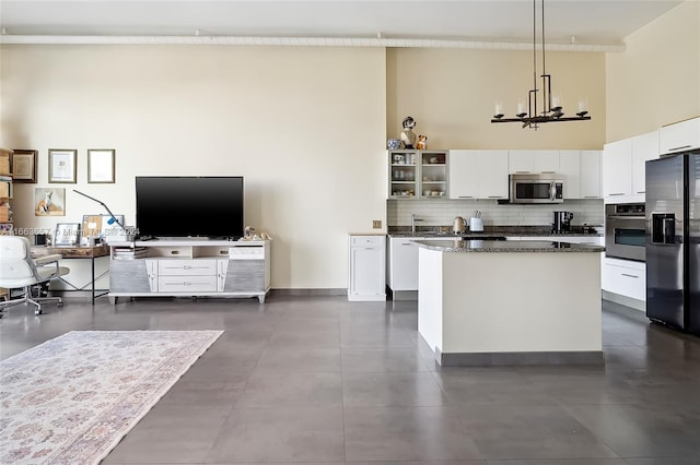 kitchen with dark stone countertops, stainless steel appliances, pendant lighting, and white cabinets