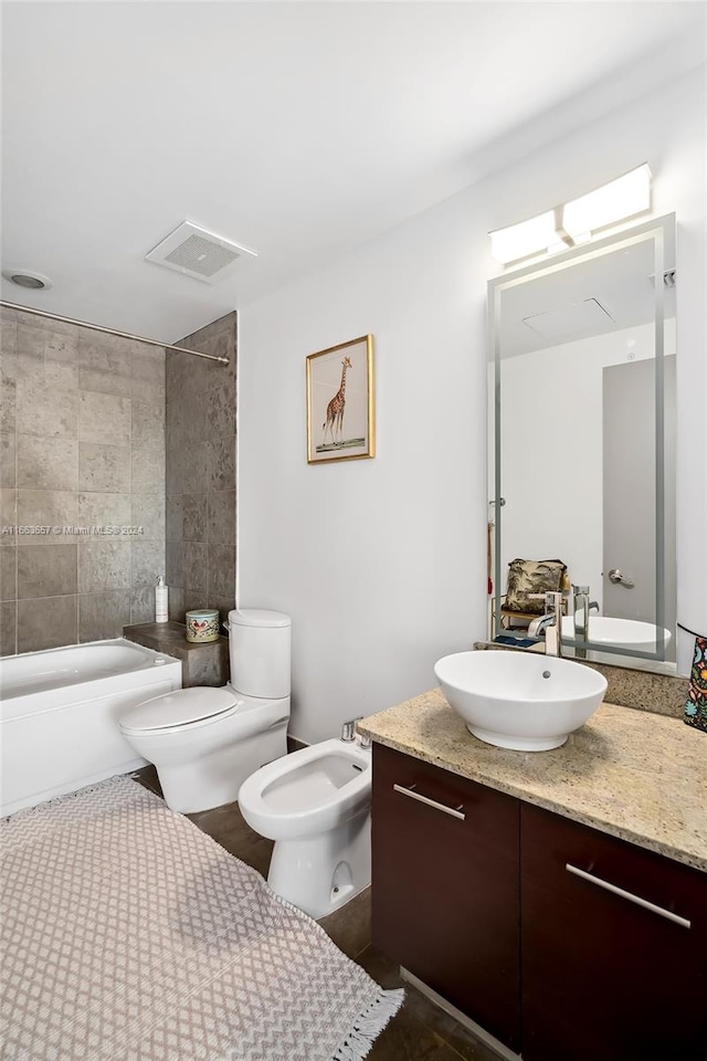 full bathroom with vanity, toilet, a bidet, and tiled shower / bath