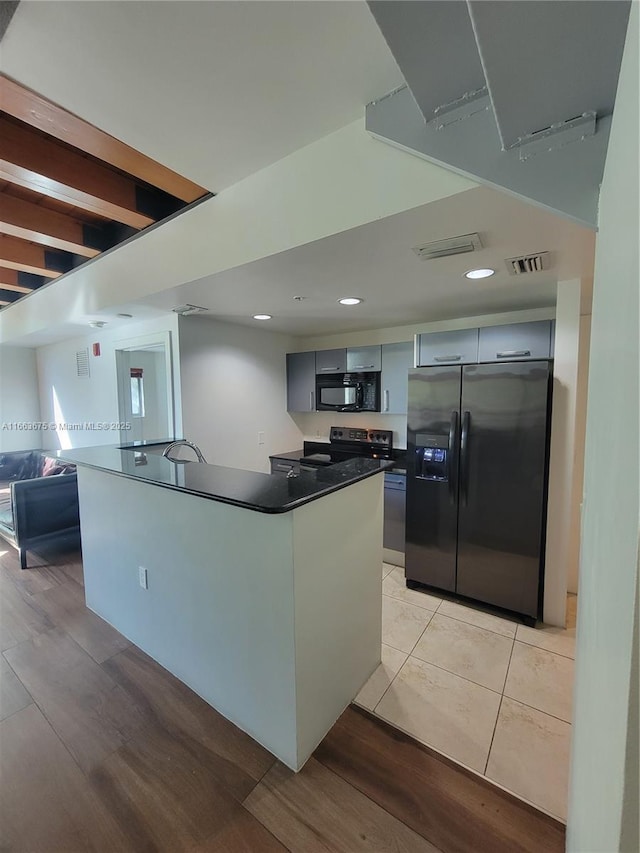 kitchen featuring gray cabinetry, stainless steel fridge, light hardwood / wood-style flooring, and range with electric stovetop