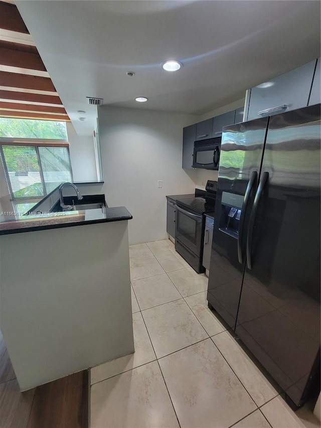 kitchen with sink, light tile patterned floors, fridge with ice dispenser, range with electric stovetop, and kitchen peninsula