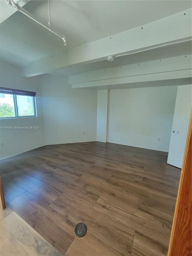 spare room featuring hardwood / wood-style floors and beamed ceiling