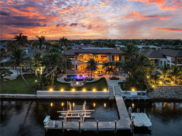 back house at dusk with a patio and a water view