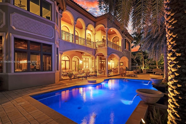 pool at dusk featuring a patio area