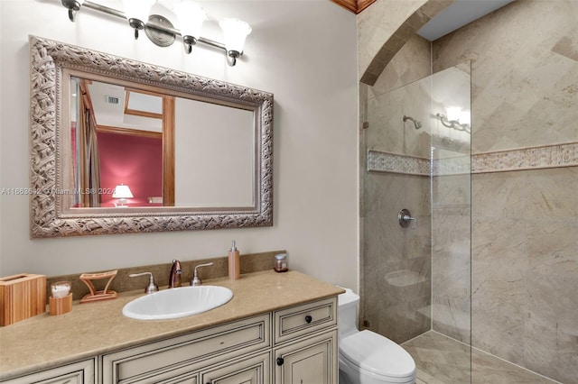 bathroom with a tile shower, vanity, and toilet