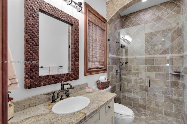 bathroom with vanity, toilet, and a shower with door