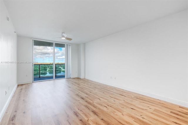 empty room featuring a wall of windows, light hardwood / wood-style floors, and ceiling fan