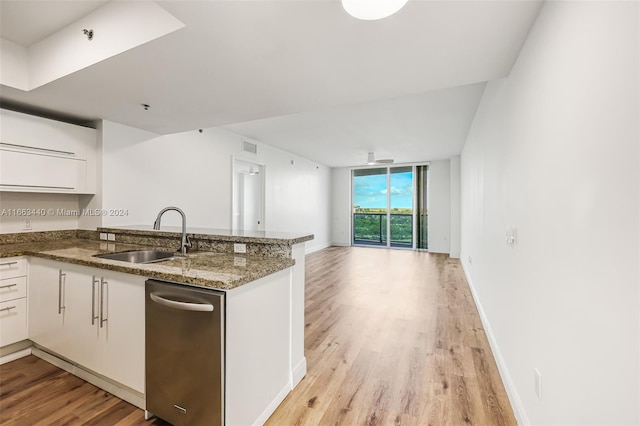 kitchen with dark stone counters, light wood-type flooring, sink, white cabinetry, and kitchen peninsula