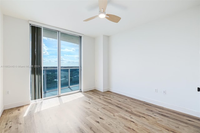 empty room with ceiling fan, expansive windows, and light hardwood / wood-style flooring