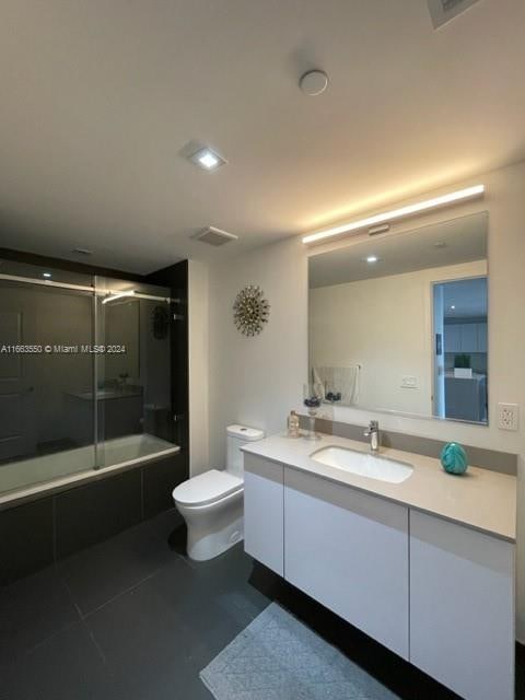 full bathroom featuring vanity, toilet, combined bath / shower with glass door, and tile patterned flooring