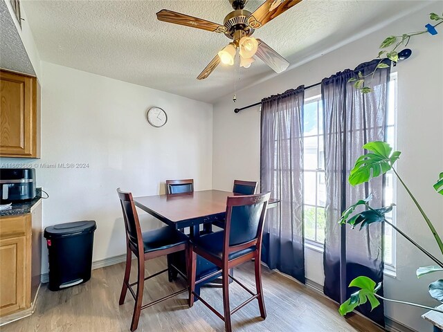 dining area featuring a textured ceiling, light hardwood / wood-style floors, ceiling fan, and plenty of natural light